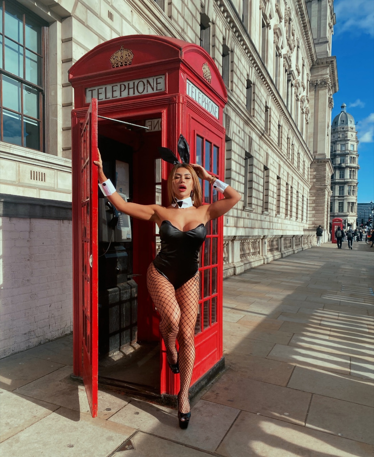 Cris Galera em uma rua de Londres ao lado de uma cabine vermelha
